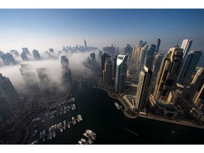 Morning fog shrouds residential and commercial skyscrapers in the Jumeirah Lake Towers and Dubai Marina districts of Dubai, United Arab Emirates, on Sunday, Jan. 17, 2021. Dubai is hoping one of the world's fastest vaccination programs and rapid testing technology will help achieve its goal of holding the Expo 2020 event this year, after the coronavirus pandemic forced a delay. Photographer: Christopher Pike/Bloomberg