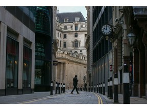 A pedestrian crosses a street in view of the Bank of England (BOE) in the City of London, U.K., on Thursday, Feb. 4, 2021. The central bank is due to release its latest decision on Thursday along with a report on how policy makers might push borrowing costs below zero.