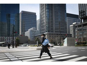 A pedestrian crosses a road near Tokyo station in Tokyo, Japan on Monday, March 7, 2022. Japan's decision to extend the duration of semi-emergency virus restrictions in Tokyo and 17 other prefectures will put further pressure on an economy that some analysts say will contract this quarter.