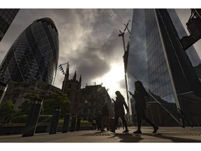Morning commuters walk past skyscrapers including 30 St. Mary Axe, also known as The Gherkin, left, in the City of London, UK, on Monday, May 16, 2022. The Office for National Statistics (ONS) will release the latest UK Labor Market Statistics on Tuesday.