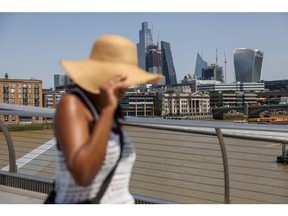 A pedestrian wearing a sunhat crosses the Millennium Bridge in London, UK, on Friday, June 17, 2022. UK temperatures may hit 34 degrees Celsius (93.2 degrees Fahrenheit) this week, a once-rare level that's becoming more common on the back of global warming.