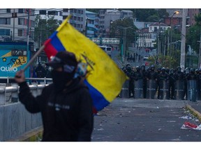A demonstrator with an Ecuadorian fmarches in front of security forces in Quito on June 22.
