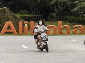 Ein Paar fährt mit einem Roller an einer Beschilderung am Hauptsitz der Alibaba Group Holding Ltd. in Hangzhou, China, vorbei.