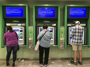 Customers use bank ATM cash machines in Toronto. Banks, authorized foreign banks and federal credit unions must now comply with new rules in dealing with customers.