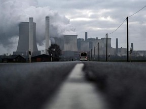 A bus drives on a road as steam rises from the cooling towers of the lignite-fired power plant of German energy giant RWE in Niederaussem, western Germany.