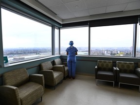 A registered nurse who has been redeployed from the operating room to the intensive care unit, looks out the window in the ICU at the Humber River Hospital in Toronto on Tuesday, April 13, 2021.