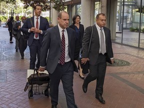 Ramesh "Sunny" Balwani, right, the former lover and business partner of Theranos CEO Elizabeth Holmes, walks into federal court in San Jose, Calif., Friday, June 24, 2022, with his lawyers and family as his criminal trial moves toward its final phase. The case alleging he joined Holmes in a scam that defrauded investors and patients who were duped about the capabilities of Theranos' flawed blood-testing technology. At front left is attorney Jeffrey Coopersmith.