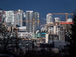 Construction cranes tower above condos under construction near southeast False Creek in Vancouver on February 9, 2020. Statistics Canada says the amount Canadians owe relative to their income pulled back in the first quarter from the record level set in the fourth quarter of 2021 as incomes grew faster than debt.