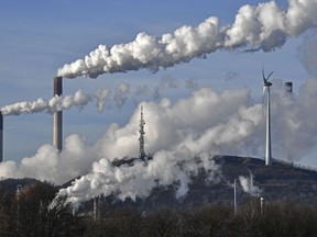 FILE - A Uniper coal-fired power plant and a BP refinery steam beside a wind generator in Gelsenkirchen, Germany, Thursday, Jan. 16, 2020. The German government wants to temporarily keep additional coal-fired power plants on stand-by for almost two years to stave off a possible electricity shortage in case natural gas supplies from Russia are suddenly reduced, officials said Wednesday, June 8, 2022.