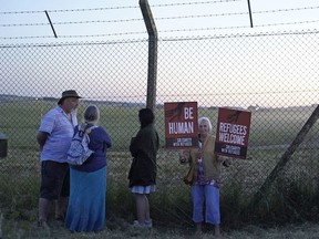 Protesters gather at the perimeter of Boscombe Down air force base in Amesbury, England on Tuesday June 14, 2022, where an aircraft is believed to be the plane set to take asylum seekers from the UK to Rwanda. Britain has cancelled its first deportation flight to Rwanda after a last-minute intervention by the European Court of Human Rights, which decided there was "a real risk of irreversible harm'' to the asylum seekers involved.