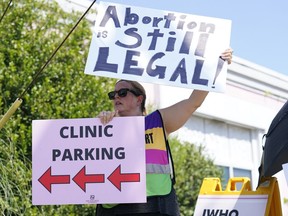 Clinic escort Kim Gibson stands outside the Jackson Women's Health Organization clinic in Jackson, Miss., calling out to incoming patients that the clinic is still open, moments after the U.S. Supreme Court ruling overturning Roe v. Wade was issued, Friday, June 24, 2022. The clinic is the only facility that performs abortions in the Mississippi. However, the ruling ends constitutional protections for abortion.