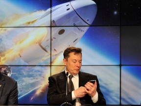 Elon Musk looks at his mobile phone at the Kennedy Space Center in Cape Canaveral, Florida