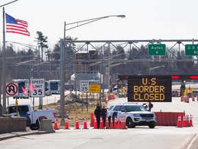 U.S. Customs officers stand beside a sign saying that the U.S. border is closed at the U.S./Canada border in Lansdowne, Ont.