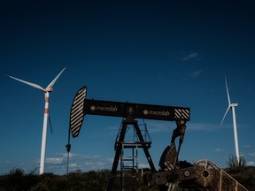 An oil drilling platform next to wind turbines at Vamcruz Windfarm in Serra do Mel, Rio Grande do Norte State, Brazil.