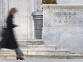 Une femme passe devant l'édifice de la Banque du Canada à Ottawa.