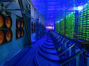 Industrial cooling fans operate to thermally regulate illuminated mining rigs at the CryptoUniverse cryptocurrency mining farm in Nadvoitsy, Russia.