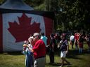 An elderly couple eat ice cream cones near a large Canadian flag during Canada Day celebrations in West Vancouver on July 1, 2019.
