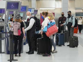 People wait in line to check in at Pearson International Airport in Toronto on Thursday, May 12, 2022. Canada's transport regulator is beefing up passenger protection rules, placing more stringent rules around reimbursement by airlines.