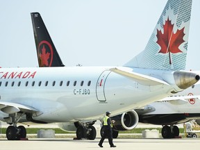 Airline ground crew walks past grounded Air Canada planes as they sit on the tarmac at Pearson International Airport, in Toronto on Tuesday, April 27, 2021. Half a million passengers sat aboard delayed international flights at Pearson in May.