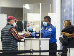 FILE - A Transportation Security Administration agent serves a traveler at a checkpoint in a sparsely populated Terminal B at LaGuardia Airport, Nov. 25, 2020, in the Queens borough of New York. Airlines are canceling more than 1,400 flights across the U.S., Thursday, June, 16, 2022, in one of the worst days yet in the summer travel season.
