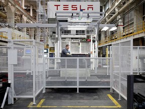 A worker watches a mechanical press line at the Tesla factory in Fremont, Calif.