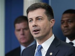 FILE - Transportation Secretary Pete Buttigieg, center, speaks during a briefing at the White House in Washington, May 16, 2022, as Labor Secretary Marty Walsh, left, and Environmental Protection Agency administrator Michael Regan, right, listen. Buttigieg says he is pushing airlines to hire more customer-service people and take other steps to help travelers this summer.