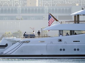 FILE - People look on from the super yacht Amadea as it arrives to the San Diego Bay Monday, June 27, 2022, seen from Coronado, Calif. The $325 million superyacht seized by the United States from a sanctioned Russian oligarch arrived in San Diego Bay on Monday. A multinational task force designed to seize Russian oligarchs' wealth has blocked and frozen $30 billion in sanctioned individuals' property and funds in its first 100 days.