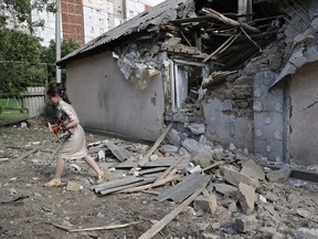 A girl carries a dog as she walks past a house damaged from shelling in the Leninsky district of Donetsk, on the territory which is under the Government of the Donetsk People's Republic control, eastern Ukraine, Monday, June 6, 2022.