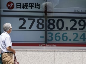 A man wearing a protective mask looks at an electronic stock board showing Japan's Nikkei 225 index at a securities firm Friday, June 10, 2022, in Tokyo. Shares were mostly lower in Asia on Friday, with only Shanghai rising, after stocks tumbled on Wall Street on expectations central banks will focus on battling inflation with interest rate hikes.