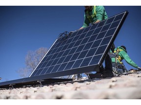A worker lays down a solar panel on a rooftop during a SolarCity Corp. residential installation in Albuquerque, New Mexico.