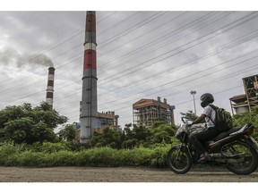 A motorcyclist travels along a road as smoke rises from a chimney at the Tata Power Co. Trombay Thermal Power Station in Mumbai, India, on Saturday, Aug. 5, 2017. Nearly six months after his turbulent elevation to run India's biggest conglomerate, Tata Chairman Natarajan Chandrasekaran is assembling a team of dealmakers to refocus some of the group's biggest businesses, expand its financial services and consumer businesses and sell or merge dozens of smaller units, according to interviews with senior executives.