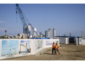 Workers walk past hoardings for the Colombo Port City, developed by China Harbour Engineering Co., a unit of China Communications Construction Co., in Colombo, Sri Lanka, on Friday, March 30, 2018. The project is one of several in Sri Lanka that offer lessons for countries looking to snag some of the more than $500 billion projected to underpin Chinese President Xi Jinping's Belt and Road infrastructure initiative.