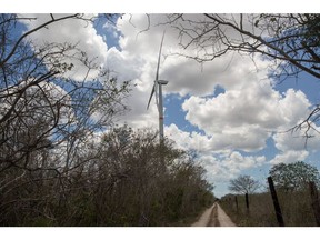 A wind turbine stands near a road in the town of Dzilam de Bravo near Merida, Yucatan, Mexico, on Saturday, May 19, 2018. At the end of the last century, before the commodities boom brought a wave of development to Latin America, opposition to the blight of new electricity infrastructure was rare. People just wanted the energy. Now that 100 percent of the region's biggest economies have access to power, the "Not in my backyard" movement--or Nimby'ism--that has long been the norm from Europe to the U.S. is creeping in here, too. Photographer: Brett Gundlock/Bloomberg