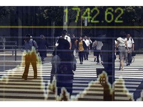 Pedestrians are reflected in an electronic stock board outside a securities firm in Tokyo, Japan, on Thursday, Aug. 30, 2018. Japan's Topix index closed lower after fluctuating as investors assessed trade frictions and geopolitical risks. Photographer: Kiyoshi Ota/Bloomberg