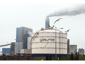 A chimney at Onyx Power coal plant chimney emits vapor beyond a gas silo storage site, operated by NV Nederlandse Gasunie, at the Port of Rotterdam in Rotterdam, Netherlands, on Tuesday, July 13, 2021. European natural gas futures retreated after hitting a record last week, pressured by weaker carbon emissions markets and as concerns over stretched shipments partially eased. Photographer: Peter Boer/Bloomberg