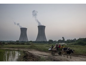 A cattle-pulled cart passes the coal-fired NTPC Ltd. Dadri Power Plant in Uttar Pradesh, India.