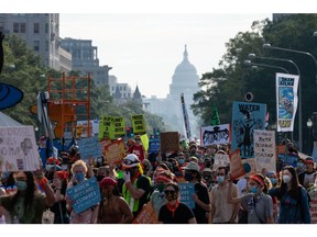Demonstrators march during a climate change rally in Washington, D.C., U.S., on Friday, Oct. 15, 2021. The White House today released a report laying out its broad ambitions for how the federal government will seek to shield the U.S. economy and financial system from threats posed by climate change.