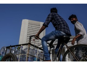 A cyclist transports empty water bottles near the Reserve Bank of India (RBI) headquarters, left, in Mumbai, India, on Saturday, Feb. 5, 2022. The RBI is set to outline its policy on Feb. 9 and is expected to take further steps like raising the reverse repo rate to further pull back on pandemic-era steps.