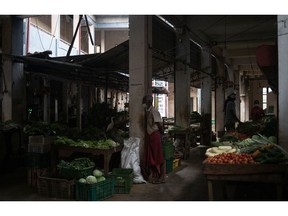 A fruit and vegetable vendor waits for customers during a daily power cut at a market in Hikkaduwa, Sri Lanka.  Photographer: Rebecca Conway/Getty Images