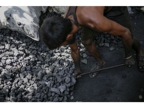 A worker loads coal into a sack at a coal wholesale market in Mumbai, India, on Thursday, May 5, 2022. Production of coal, the fossil fuel that accounts for more than 70% of India's electricity generation, has failed to keep pace with unprecedented energy demand from the heat wave and the country's post-pandemic industrial revival.