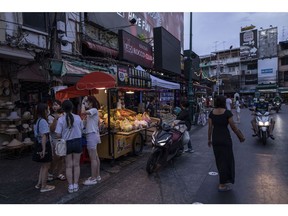 Tourists stand next to a fruit vendor on Khaosan Road in Bangkok, Thailand, on Saturday, July 2, 2022. Foreign tourist arrivals into Thailand are set to beat official forecasts with the lifting of pandemic-era restrictions, a rare positive for the nation's Covid-battered economy and currency.
