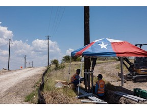 Workers install infrastructure under a Texas flag tent during a heatwave in Austin, Texas, on July 11.