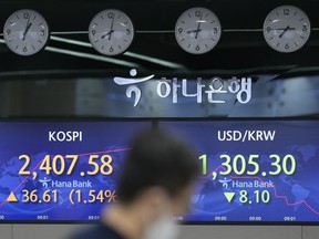 A currency trader walks near the screens showing the Korea Composite Stock Price Index (KOSPI), left, and the foreign exchange rate between U.S. dollar and South Korean won at a foreign exchange dealing room in Seoul, South Korea, Wednesday, July 20, 2022. Asian shares advanced Wednesday after Wall Street rallied to its best day in more than three weeks as companies reported strong profits for the past quarter.