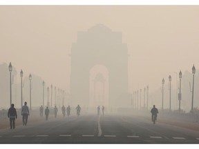 Pedestrians walk along Rajpath boulevard as India Gate monument stands shrouded in smog in New Delhi, India, on Tuesday, Nov. 5, 2019. Air pollution levels in India's capital remained at near record levels, forcing schools to shut down through mid week and keeping residents indoors, as the nation grapples for solutions. Photographer: Bloomberg/Bloomberg