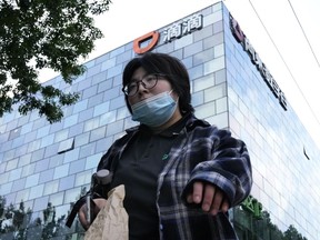 FILE - A woman walks past the headquarters for Didi Beijing on July 16, 2021. China's internet watchdog has fined ride-hailing firm Didi Global more than 8 billion yuan ($1.2 billion) following an investigation into the company's cybersecurity practices.