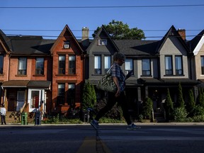 A person walks by a row of houses in Toronto on Tuesday July 12, 2022. The Bank of Canada increased its key interest rate by one percentage point Wednesday in the largest hike the country has seen in 24 years.THE CANADIAN PRESS/Cole Burston