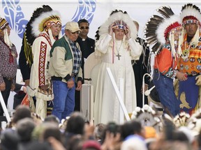 Pope Francis dons a headdress during a visit with Indigenous peoples at Maskwaci, the former Ermineskin Residential School, Monday, July 25, 2022, in Maskwacis, Alberta. Pope Francis traveled to Canada to apologize to Indigenous peoples for the abuses committed by Catholic missionaries in the country's notorious residential schools.