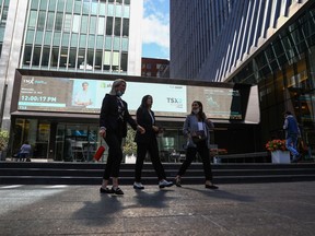 A sign board displays the TSX as women walk past the Richmond Adelaide Centre in the financial district in Toronto on Wednesday, September 29, 2021.