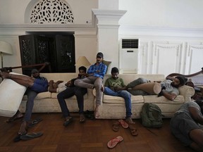 Protesters rest on sofas in the living hall of prime minister's official residence a day after vandalising it in Colombo, Sri Lanka, Sunday, July 10, 2022. Sri Lanka's president and prime minister agreed to resign Saturday after the country's most chaotic day in months of political turmoil, with protesters storming both officials' homes and setting fire to one of the buildings in a rage over the nation's severe economic crisis.