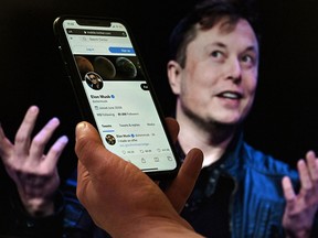 A phone screen displays the Twitter account of Elon Musk with a photo of him shown in the background. Musk said on Friday he was terminating his US$44 billion deal for Twitter Inc.